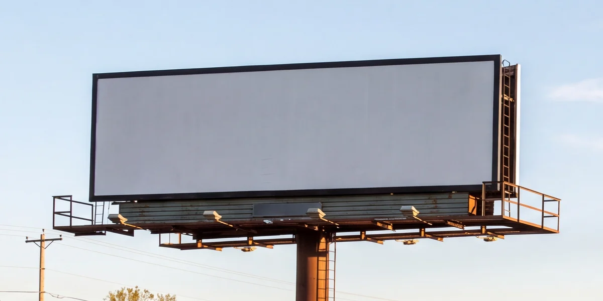 Photo of billboard face B-114 N, blank, on a single steel pole beside a four-lane highway